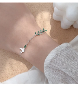 Détail du bracelet hirondelle en argent S925 avec branche d'olivier verte sur le poignet
