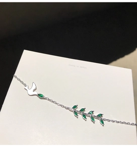 Détail macro du pendentif hirondelle et branche d'olivier en argent s925 avec gemmes