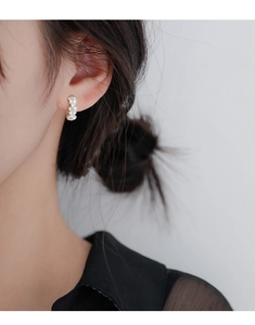 Gros plan de boucles d'oreilles fleur en argent S925 sur l'oreille d'un mannequin