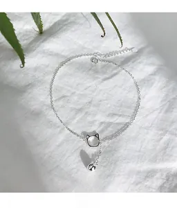 Dettaglio della cavigliera in argento S925 con pendente a gatto e campanellino su lino