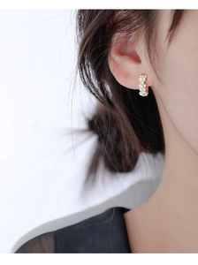 Détail de boucles d'oreilles en argent avec zircons blancs portées à l'oreille, vue macro