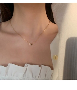 Détail du collier avec pendentif infini serti de pierres sur une chaîne dorée