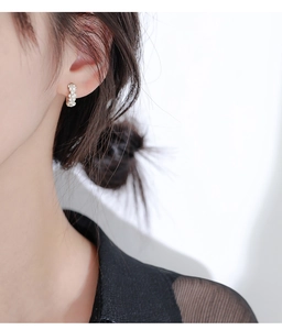 Détail de petites boucles d'oreilles huggie en argent avec breloques fleurs étincelantes