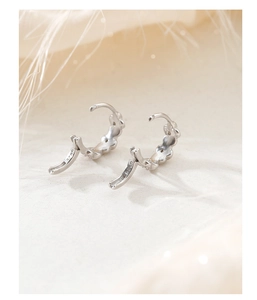 Détail macro de créoles en argent sterling S925 avec un motif délicat de pétales