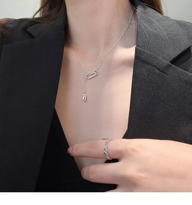 Dettaglio della collana a graffetta in argento con zirconi indossata su un abito nero