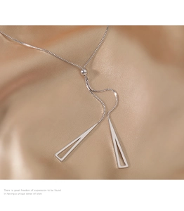 Macro detail of S925 silver geometric triangle pendants and adjustable box chain on silk