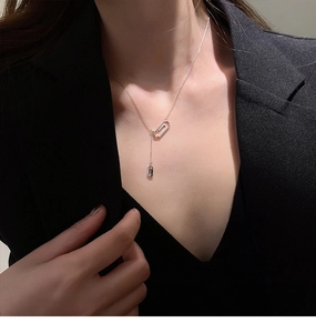 Dettaglio macro di una collana a graffetta in argento con zirconi su un blazer nero
