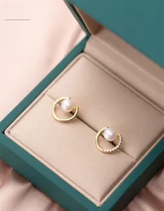 Detailed close-up of semi-circular S925 silver pearl earrings with sparkling diamond accents