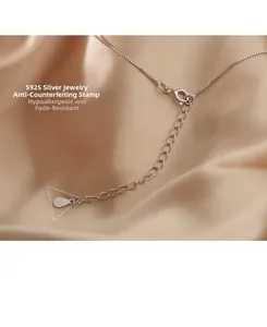 Macro shot of S925 sterling silver lobster clasp and extension chain on champagne silk