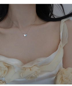 Gros plan d'un collier papillon argenté avec ailes en nacre bleue et blanche sur modèle