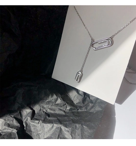 Dettaglio macro di una collana a graffetta in argento con zirconi brillanti su carta nera