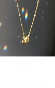 Detail of gold circular pendant with crystal accents and delicate beaded chain