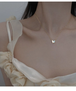 Détail d'un collier papillon avec pendentif en nacre irisée porté sur le cou d'une femme