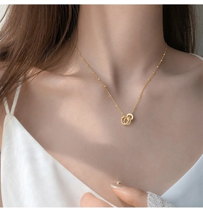Close-up of gold double interlocking ring necklace with satellite chain on female neck