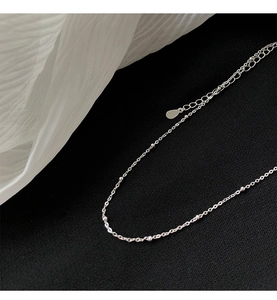 Vue macro du collier à perles argentées avec pendentif goutte et chaîne de réglage