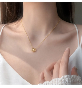 Detail of minimalist gold-plated triple interlocking ring pendant on a delicate beaded chain