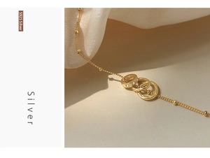 Detail of S925 silver interlocking rings pendant on gold beaded chain with cubic zirconia