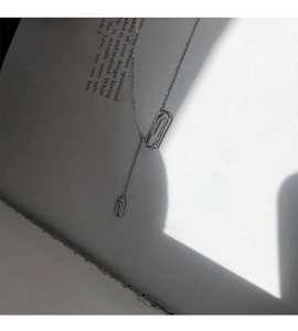 Dettaglio artistico di una collana con ciondolo a graffetta in argento e zirconi su un libro