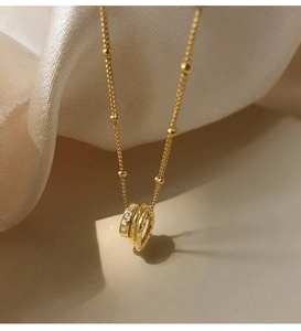 Close-up of golden triple-interlocking ring pendant with sparkling zircon on silk