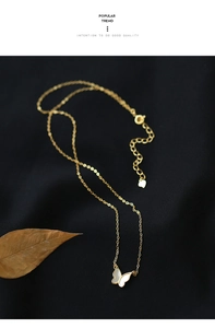 Détail d'un collier papillon doré avec incrustation de nacre sur un tissu noir élégant