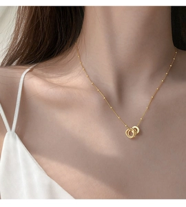 Close-up of golden interlocking double ring pendant necklace on satellite chain