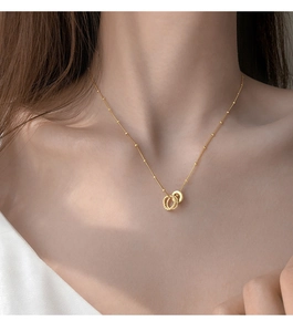 Detail view of gold double-ring necklace on a model showing beaded chain texture