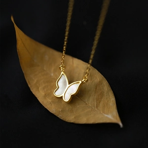 Collier minimaliste à pendentif papillon doré avec nacre blanche sur une feuille