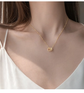 Close-up of golden interlocking rings necklace with textured and smooth finishes
