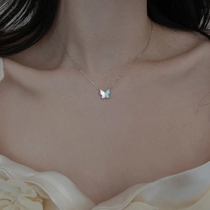 Collier papillon argenté avec pendentif en nacre blanche et bleue porté par un mannequin