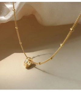 Close-up of minimalist gold ring pendant necklace with cubic zirconia on silk background