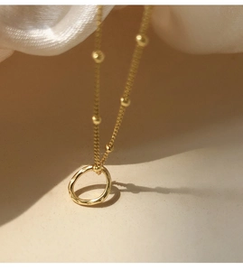 Detailed close-up of a gold satellite chain necklace featuring a hammered circle pendant
