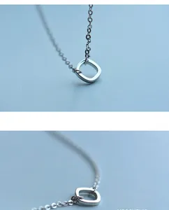 Detail view of square silver pendant with fine cross chain in minimalist design