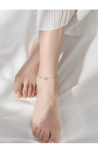 Close-up of minimalist silver geometric square anklet worn on ankle with soft fabric