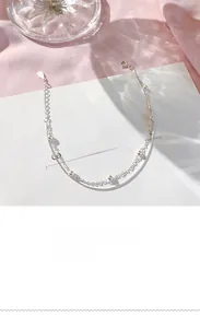 Detailed view of silver double-layered bracelet with delicate beads on white card background