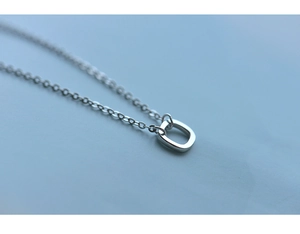 Detailed close-up of a minimalist S925 sterling silver square pendant on a delicate chain