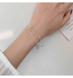 Detailed view of a silver double-layer bracelet with smooth snake chain and small beads