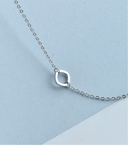 Macro shot of silver square geometric pendant necklace on a blue textured background