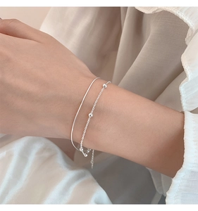Detailed close-up of double-layer silver bracelet with minimalist round beads on wrist