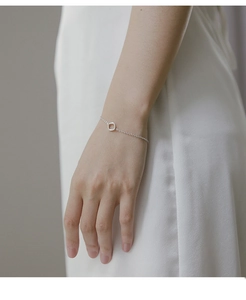 Close-up of minimalist silver bracelet with hollow square pendant on model wrist