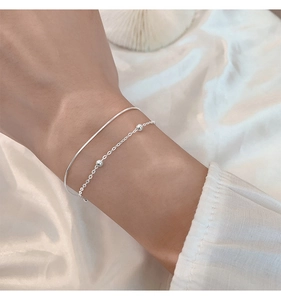 Close-up of a double-layered silver bracelet with round beads on silk background