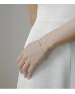 Detail view of minimalist silver chain bracelet with flat circle charm on model wrist