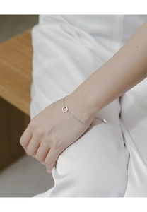 Close-up of minimalist sterling silver bracelet featuring a hollow square charm on a fine chain