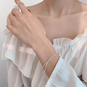 Minimalist silver double-layer bead bracelet and wavy ring set on a female model