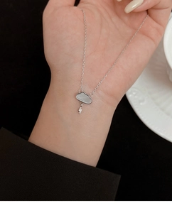 Macro view of mother of pearl cloud necklace with lightning pendant on hand