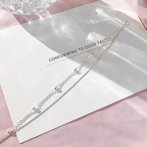 Double-layer silver chain bracelet with small beads and heart pendant on silk background