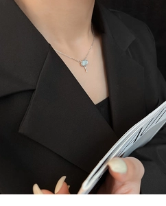 Close-up of mother-of-pearl cloud pendant on silver necklace worn over black suit