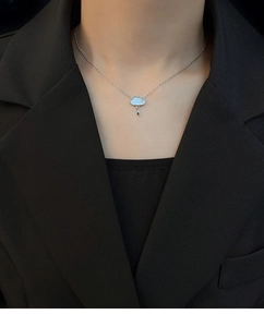 Detailed view of silver cloud and lightning pendant necklace with mother of pearl inlay
