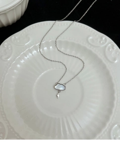 Detail view of cloud-shaped mother of pearl pendant with lightning bolt on silver chain