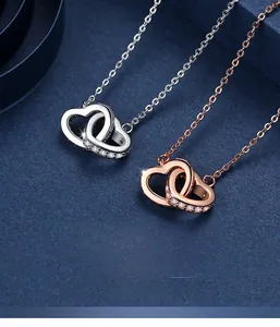 Detail of interlocking S925 silver and rose gold double heart pendants on dark background