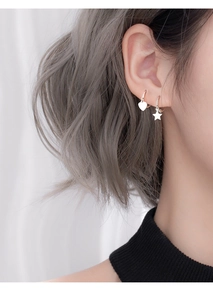 Close-up of a model wearing 925 silver heart and star pendant earrings on earlobe